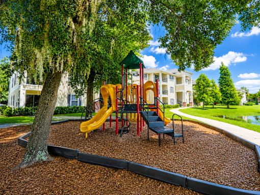 A playground with a yellow slide and a green canopy.