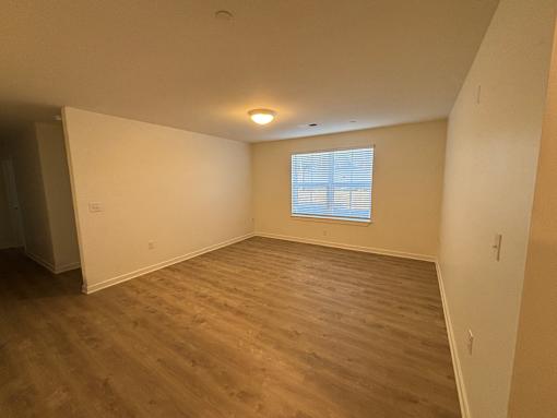 A room with wooden flooring and a window with blinds.