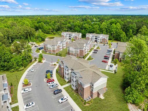 A large apartment complex with a parking lot in front.
