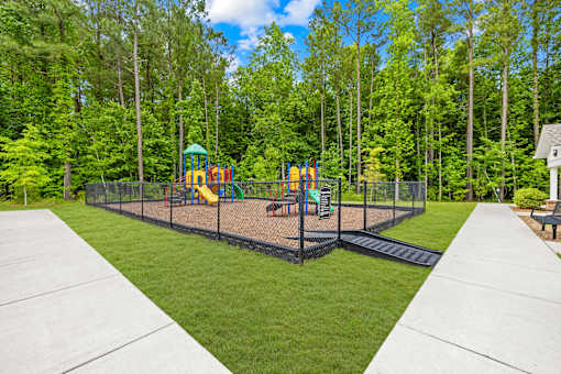 A playground with a swing set and slide in the middle of a grassy area.