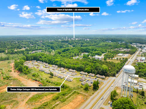 A bird's eye view of a residential area with a water tower and a road leading to a town.