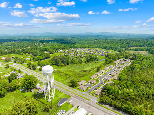 A water tower stands in a green field next to a road.
