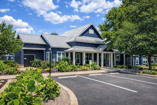 A blue building with a grey roof and a parking lot in front.