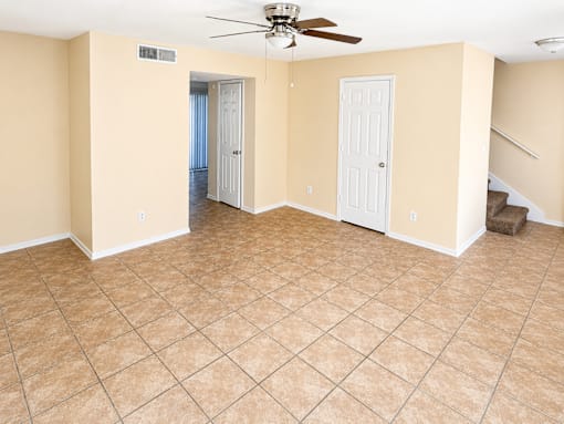 A room with a ceiling fan and tile flooring.