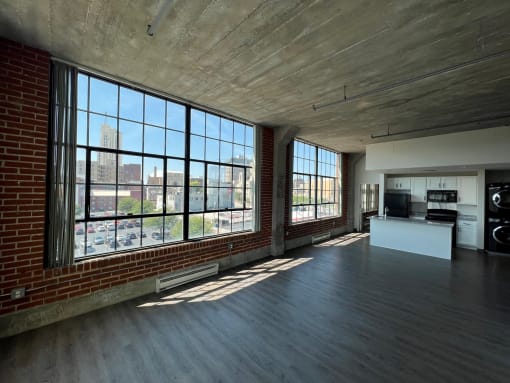 an open living room with large windows and a kitchen