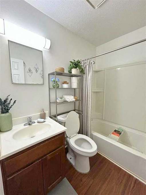 A white toilet sits in a bathroom next to a sink and a bathtub.
