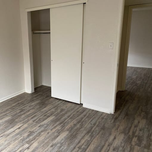 A white closet door is open in a room with a wooden floor.