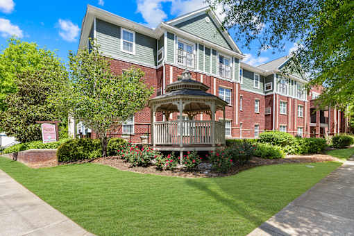 A red brick building with a gazebo in the front yard.