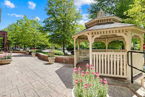 A gazebo is surrounded by a brick patio and a black railing.
