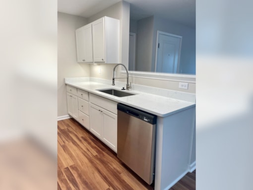 a kitchen with white cabinets and a stainless steel dishwasher