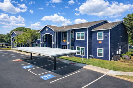 A parking lot with a blue building and a covered parking area.
