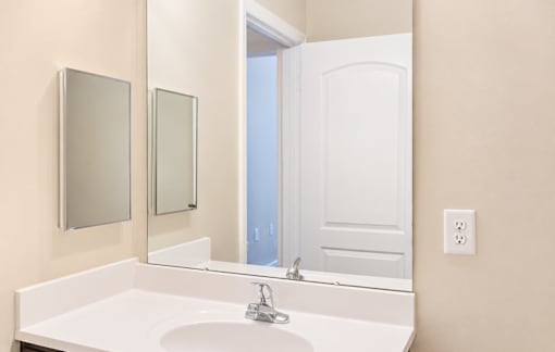 A white sink in a bathroom with a white door and two mirrors.