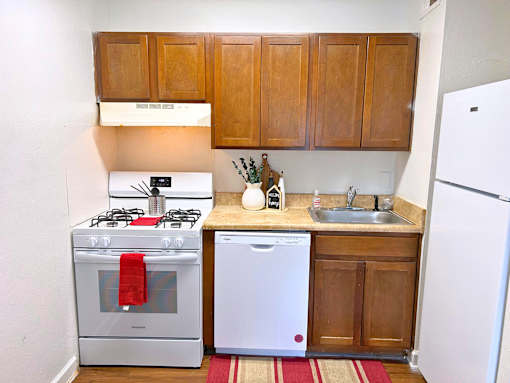 A small kitchen with a white refrigerator, a white dishwasher, and a white stove.