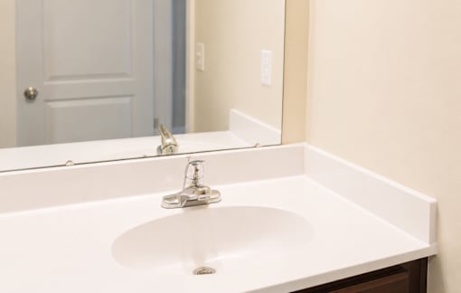 A white sink in a bathroom with a mirror above it.