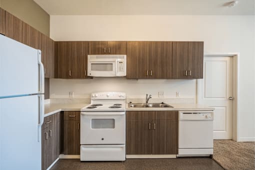 A kitchen with white appliances and brown cabinets.
