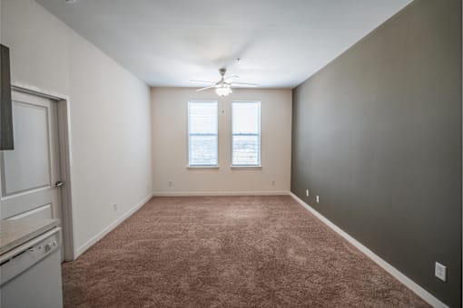 A room with a carpeted floor and a window with blinds.