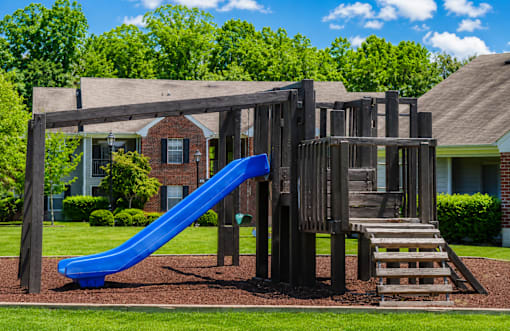 A playground with a blue slide and a wooden structure.