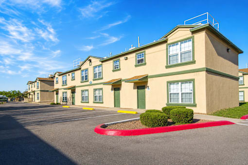 A row of beige apartment buildings with green trim and a red circle in the parking lot.