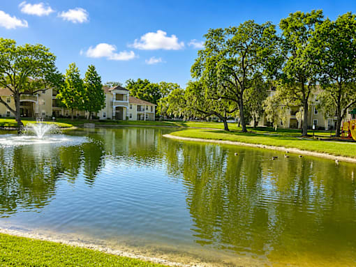 A serene lake in a park with a building in the background.