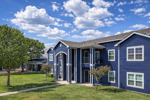 A blue building with a white trim and a tree in front.