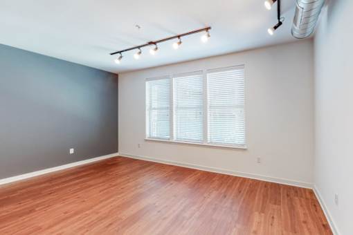 A room with wooden flooring and a window with blinds.