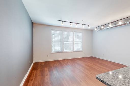 A room with wooden flooring and a window with blinds.