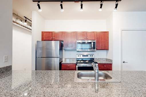 A kitchen with a stainless steel refrigerator, microwave, oven, and sink.