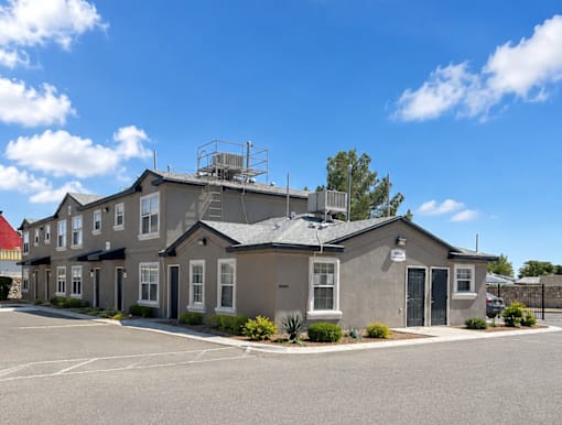 A building with a grey roof and a parking lot in front.
