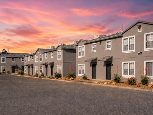 A row of houses with a pink and purple sky in the background.