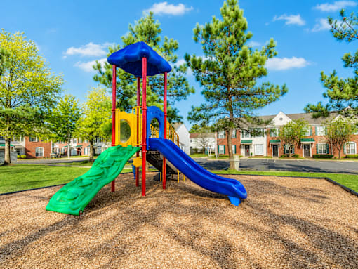 A playground with a blue and green slide and a yellow platform.