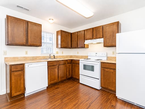 A kitchen with white appliances and wooden cabinets.