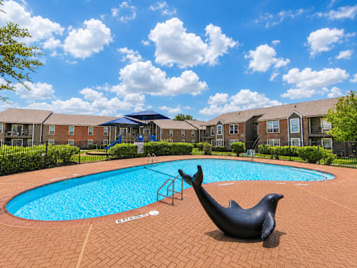 A pool with a seal statue in front of apartment buildings.