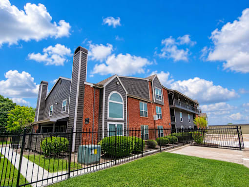 A large brick house with a black fence in front.