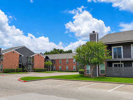 A parking lot in front of a brick apartment building.