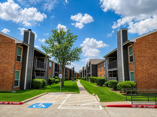 A row of apartment buildings with a blue handicap parking sign in the foreground.