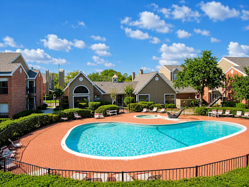 A swimming pool surrounded by a black fence and lounge chairs.