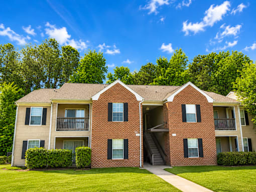 A two-story brick apartment building with a green lawn in front.