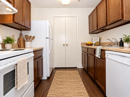 A kitchen with white appliances and brown cabinets.