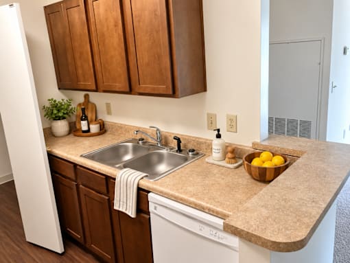 A kitchen with a sink, a bowl of lemons, and wooden cabinets.