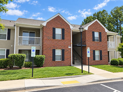 A red brick apartment building with a parking sign in front.