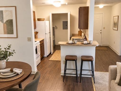 A kitchen with a bar stool and a fridge.