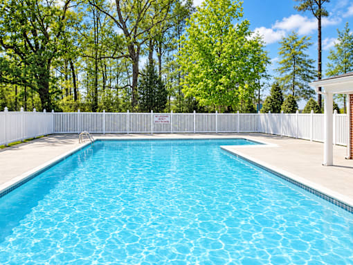 A rectangular pool with a white fence around it.