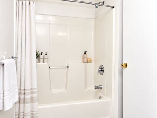 A white bathroom with a white tub and a white towel hanging on the side.
