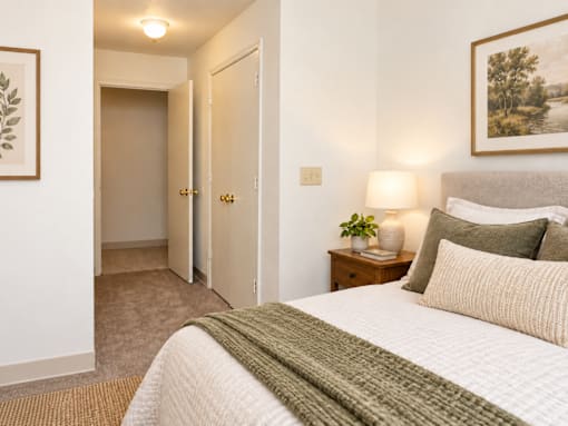 A bedroom with a bed, lamp, and painting on the wall.