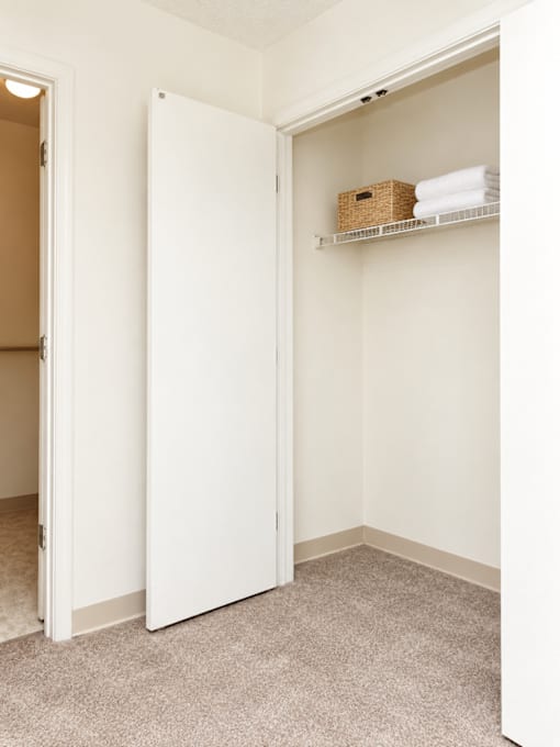 A white closet with a shelf and a basket on it.
