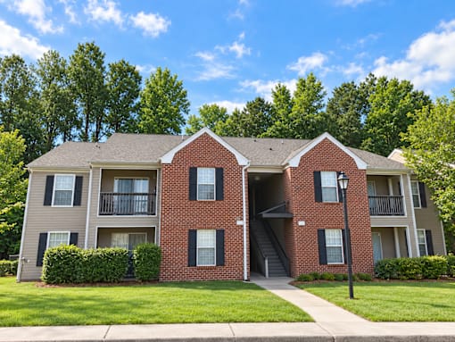 A red brick apartment building with a green lawn in front.