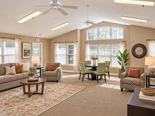 A living room with a sofa, chairs, a dining table, and a ceiling fan.