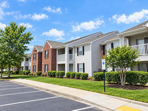 A row of apartment buildings with a parking lot in front.
