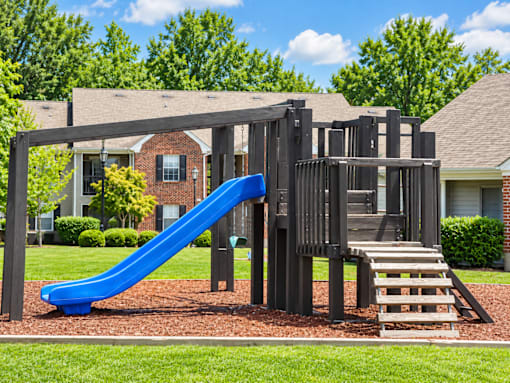 A playground with a blue slide and a wooden structure.