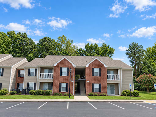 A row of apartment buildings with a parking lot in front.